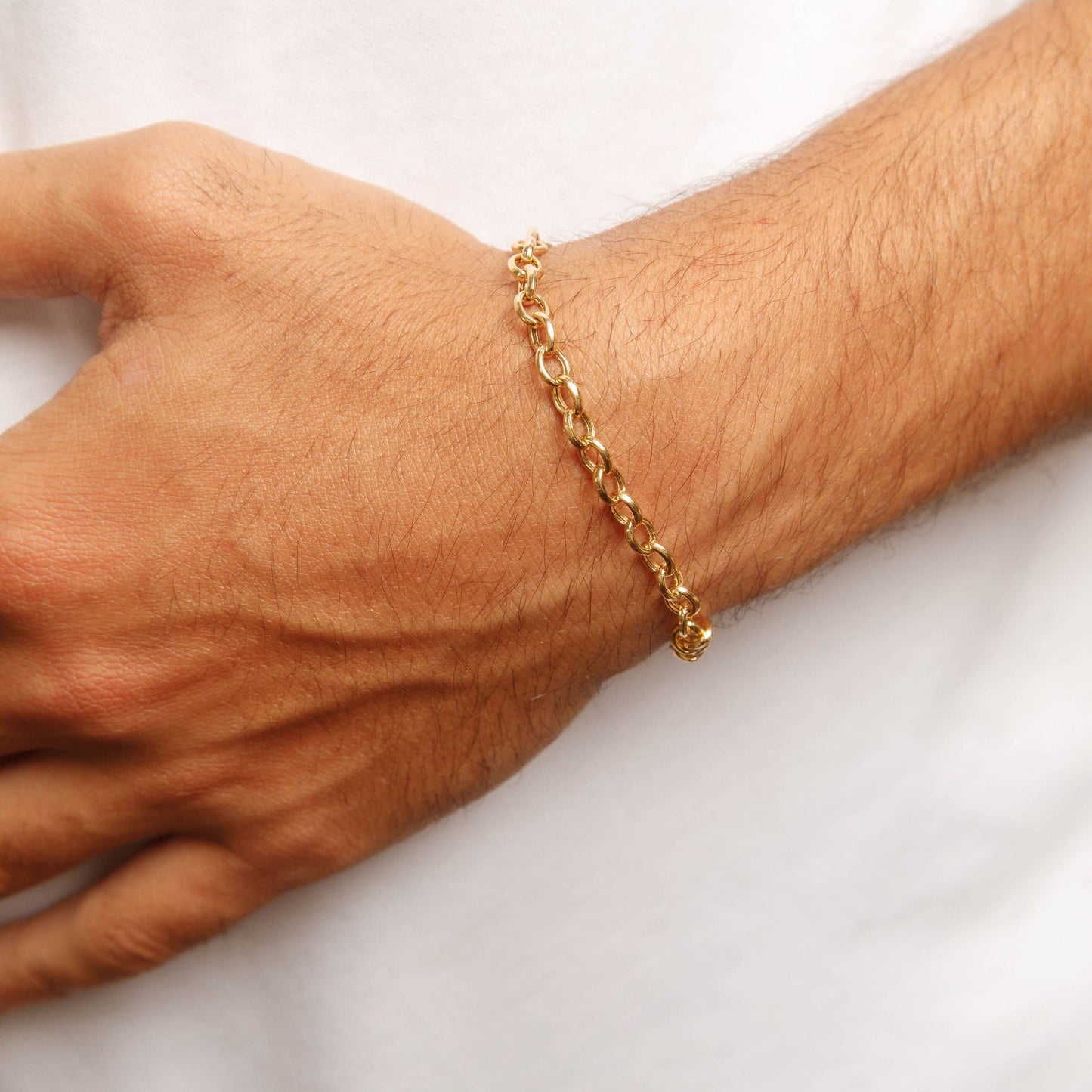 Gold bracelet on a person's wrist against a white background
